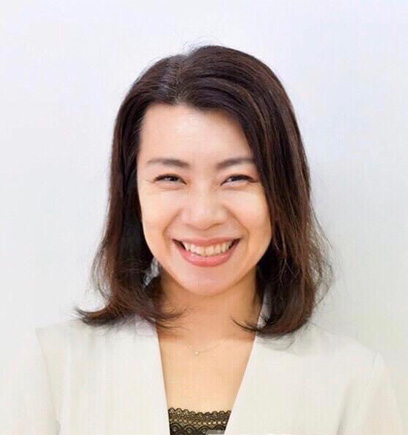 Portrait of a smiling Asian woman with shoulder-length dark hair, wearing a white blazer and looking at the camera.